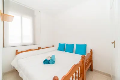 a bedroom with a bed with blue pillows and shoes at Apartamento Acqua Fresca in Cunit