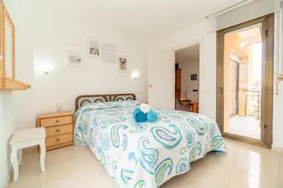 a bedroom with a bed with a blue and white comforter at Apartamento Acqua Fresca in Cunit