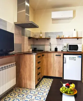 a kitchen with wooden cabinets and a bowl of fruit on a table at La Llar de la Kim, ideal familias in Arenys de Mar
