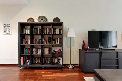 a book shelf filled with books next to a television at Frida by EnjoyApartments in Barcelona
