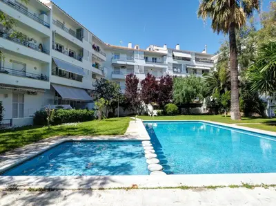 an apartment with a swimming pool in front of a building at Llopart Apartment by Hello Homes Sitges in Sitges