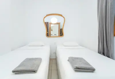 a bathroom with two white beds and a mirror at Canela Homes BARCELONA GÒTIC in Barcelona