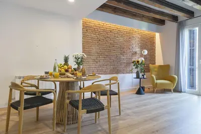 a dining room with a table and chairs and a brick wall at Canela Homes BARCELONA STYLE in Barcelona