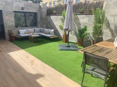 a backyard with green grass and an umbrella at Matarolux26 in Mataró