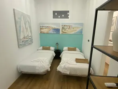 two beds in a room with paintings on the wall at Matarolux26 in Mataró