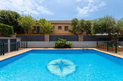a swimming pool with a umbrella in the water at Aparthotel Vilassar in Vilassar de Mar