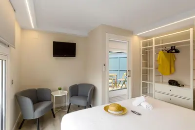 a bedroom with a bed and two chairs and a television at Aparthotel Vilassar in Vilassar de Mar