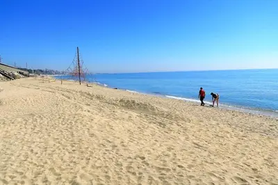 two people walking on a sandy beach near the ocean at OASIS BEACH-CITY apartment in Montgat