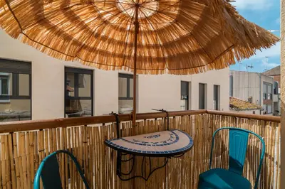 a table and chairs under an umbrella on a balcony at OASIS BEACH-CITY apartment in Montgat