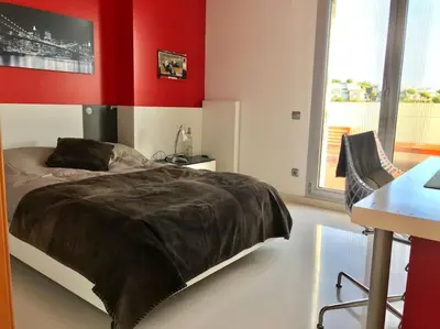 a bedroom with a bed and a red wall at Sitges espectacular vista al mar in Sant Pere de Ribes