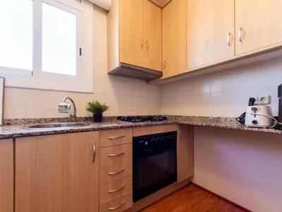 a kitchen with wooden cabinets and a sink at Apartment Garbi by Interhome in Cunit