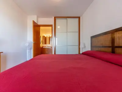 a bedroom with a large bed with a red blanket at Apartment Garbi by Interhome in Cunit