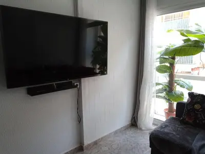 a flat screen tv hanging on a wall in a living room at GARDEN'S SEA PiNEDA DE MAR in Pineda de Mar
