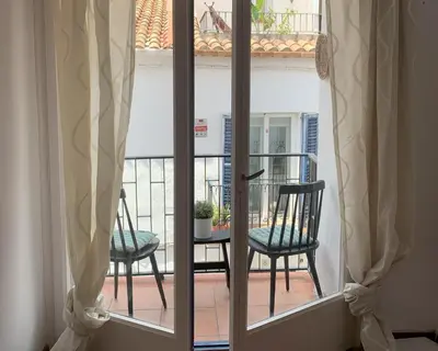 a window with two chairs sitting on a balcony at Migjorn Apartment a place in the heart of Sitges in Sitges