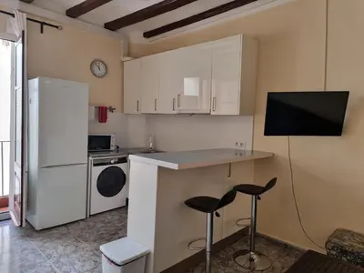 a kitchen with white cabinets and a counter with stools at Apartment in Downtown 2 bedrooms AC 30 nigths min in Barcelona