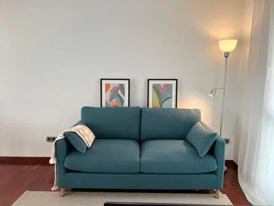 a blue couch in a living room with two pictures at Opening Doors Premiá Beach - Sol & playa cerca Barcelona in Premiá de Mar