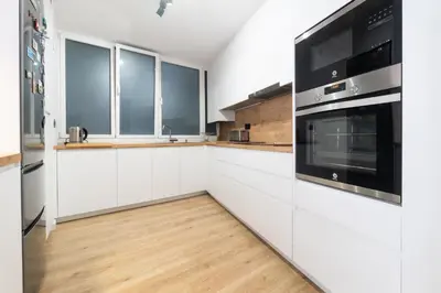 a kitchen with white cabinets and black appliances at Apartamento Granollers in Granollers