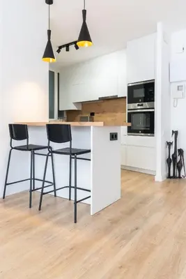 a kitchen with white cabinets and black bar stools at Apartamento Granollers in Granollers