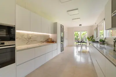 a kitchen with white cabinets and marble counter tops at Sea View Villa with Spa & BBQ in Badalona