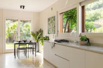 a white kitchen with a table and a window at Sea View Villa with Spa & BBQ in Badalona