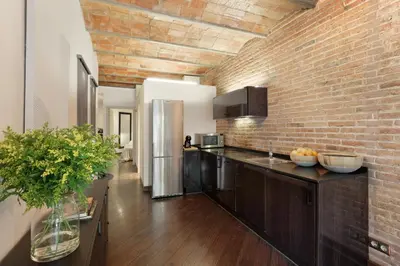 a kitchen with a brick wall and a refrigerator at Enjoy Apartments Urban Retreat Valencia 1 in Barcelona