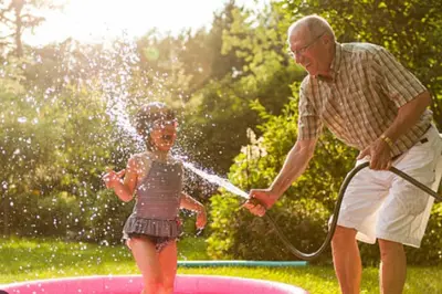 a man spraying a little girl with a hose at Casa Nina junto Barcelona Centro y playa in Teià