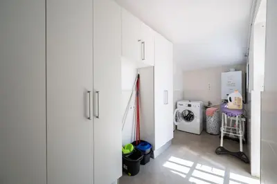a laundry room with white cabinets and a washing machine at Casa Nina junto Barcelona Centro y playa in Teià