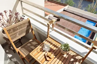 a wooden chair sitting on a balcony next to a pool at Cerca de la Playa y El Born, con Piscina in Barcelona