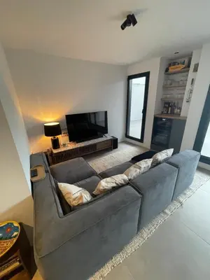 a living room with a gray couch and a flat screen tv at Apartamento de una habitación con terraza grande cerca de Barcelona in Badalona