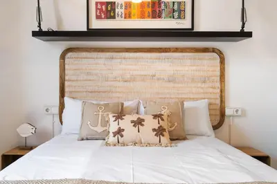 a bedroom with a white bed with a large headboard at Lodging Apartments Almirall Beach 52 in Barcelona