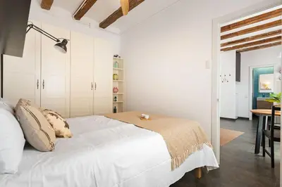 a white bedroom with a bed and a table at Lodging Apartments Almirall Beach 52 in Barcelona