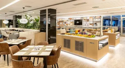 a restaurant with tables and chairs and a bar at Ilunion Barcelona in Barcelona
