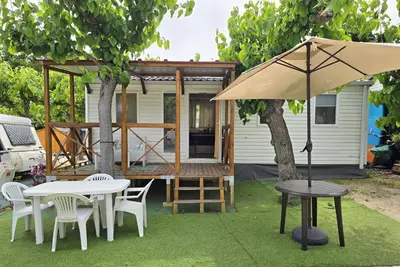 a house with a table and chairs and an umbrella at Camping Costa Dorada Bungalow Maia in Canet de Mar