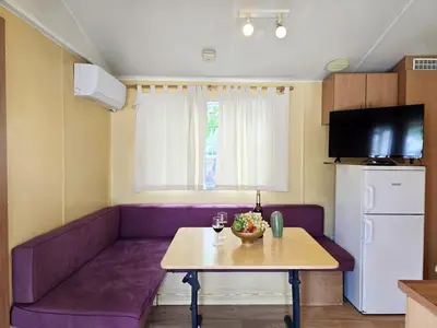 a living room with a purple couch and a table at Camping Costa Dorada Bungalow Maia in Canet de Mar