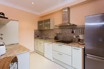a kitchen with white cabinets and a stainless steel refrigerator at Charming Central Apartment Big Sunny Terrace! in Barcelona