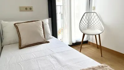 a bedroom with a bed with a chair next to a window at Dúplex 2 hab con terraza by Prestigi in Terrassa