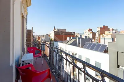 a balcony with red chairs and a view of a city at Bonito alojamiento cerca de Plaza España in Barcelona