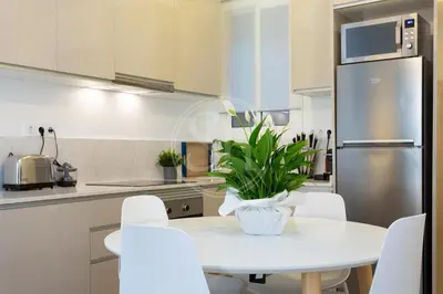 a kitchen with a white table and white chairs at Apartamento cerca de Sagrada Familia in Barcelona