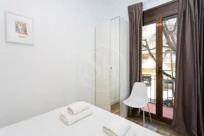 a white bedroom with a white bed and a window at Apartamento cerca de Sagrada Familia in Barcelona