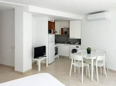 a white kitchen with a white table and chairs at M2 Apartament cèntric in Terrassa