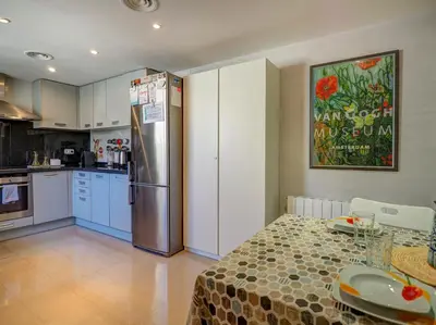 a kitchen with a table and a stainless steel refrigerator at La Perla by Hello Homes Sitges in Sitges