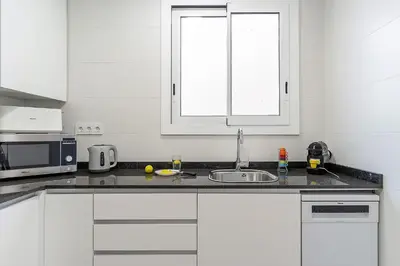 a white kitchen with a sink and a microwave at 4213 - AB Sagrada Familia Views VI-I in Barcelona