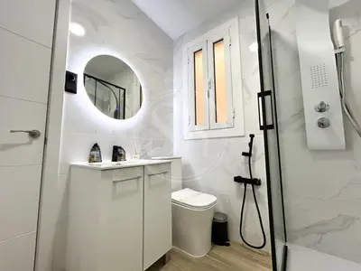 a white bathroom with a toilet and a mirror at Wonderful apartment Enamorats in Barcelona