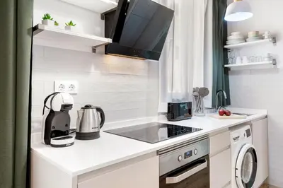 a white kitchen with a stove top oven next to a sink at Lodging Apartments Almirall Beach 31 in Barcelona