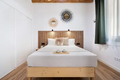 a bedroom with a large white bed with a wooden headboard at Lodging Apartments Almirall Beach 21 in Barcelona
