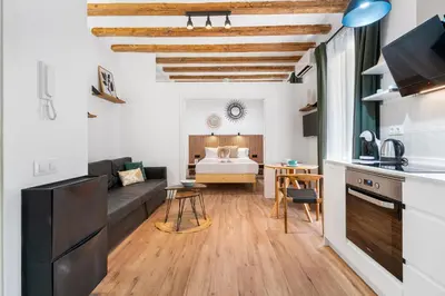 a kitchen and living room with a bed in the background at Lodging Apartments Almirall Beach 21 in Barcelona