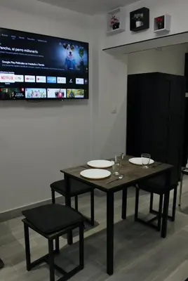 a dining room with a table and chairs and a screen at Work Stay in Gavà