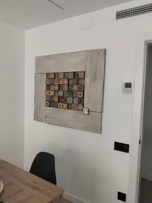 a painting on a white wall with a wooden table at Vidanova 2 in Vilanova i la Geltrú