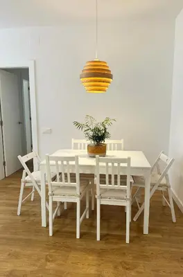 a white dining room table with white chairs and a potted plant at Barcelona a 20 minutos en piso reformado y soleado in Gavà