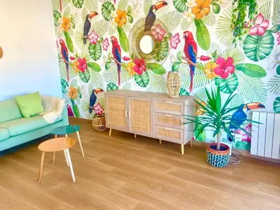 a living room with a blue couch and a colorful wallpaper at Tucan tropical in Sabadell